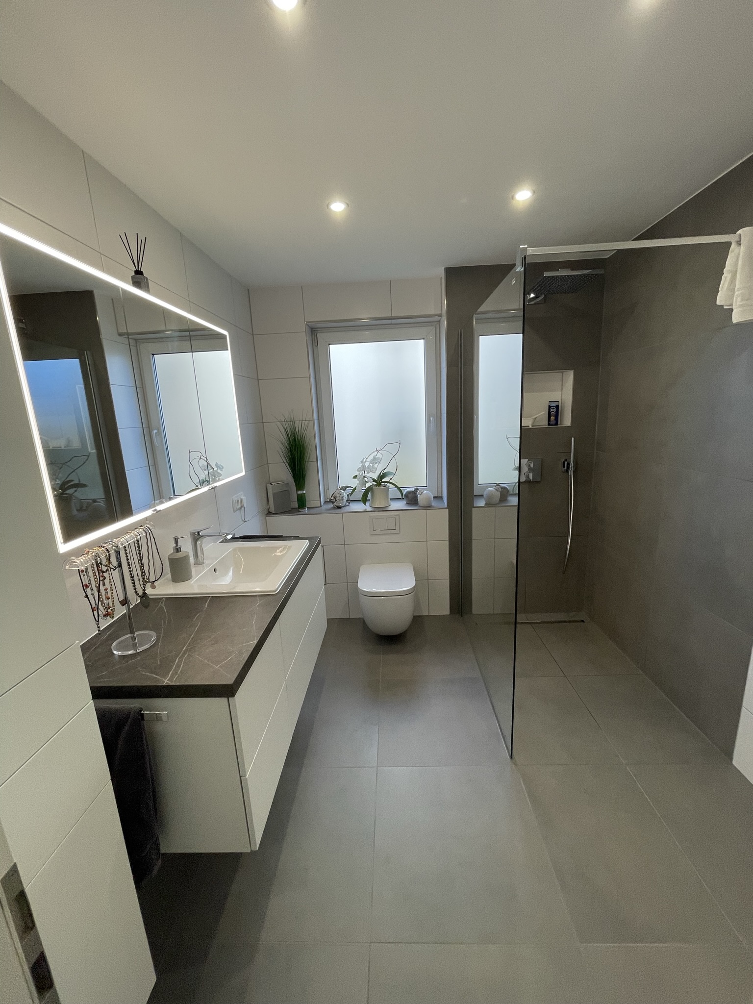 Fertiggestelltes Hauptbad mit Walk-In-Dusche, Geberit CleanLine und LED-Spiegelschrank