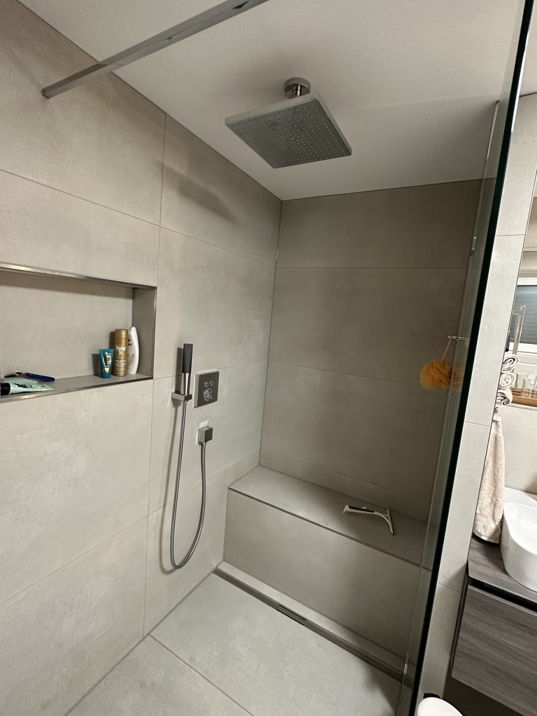 Begehbare Dusche mit Glasabtrennung, Sitzgelegenheit und beleuchteter Nische
