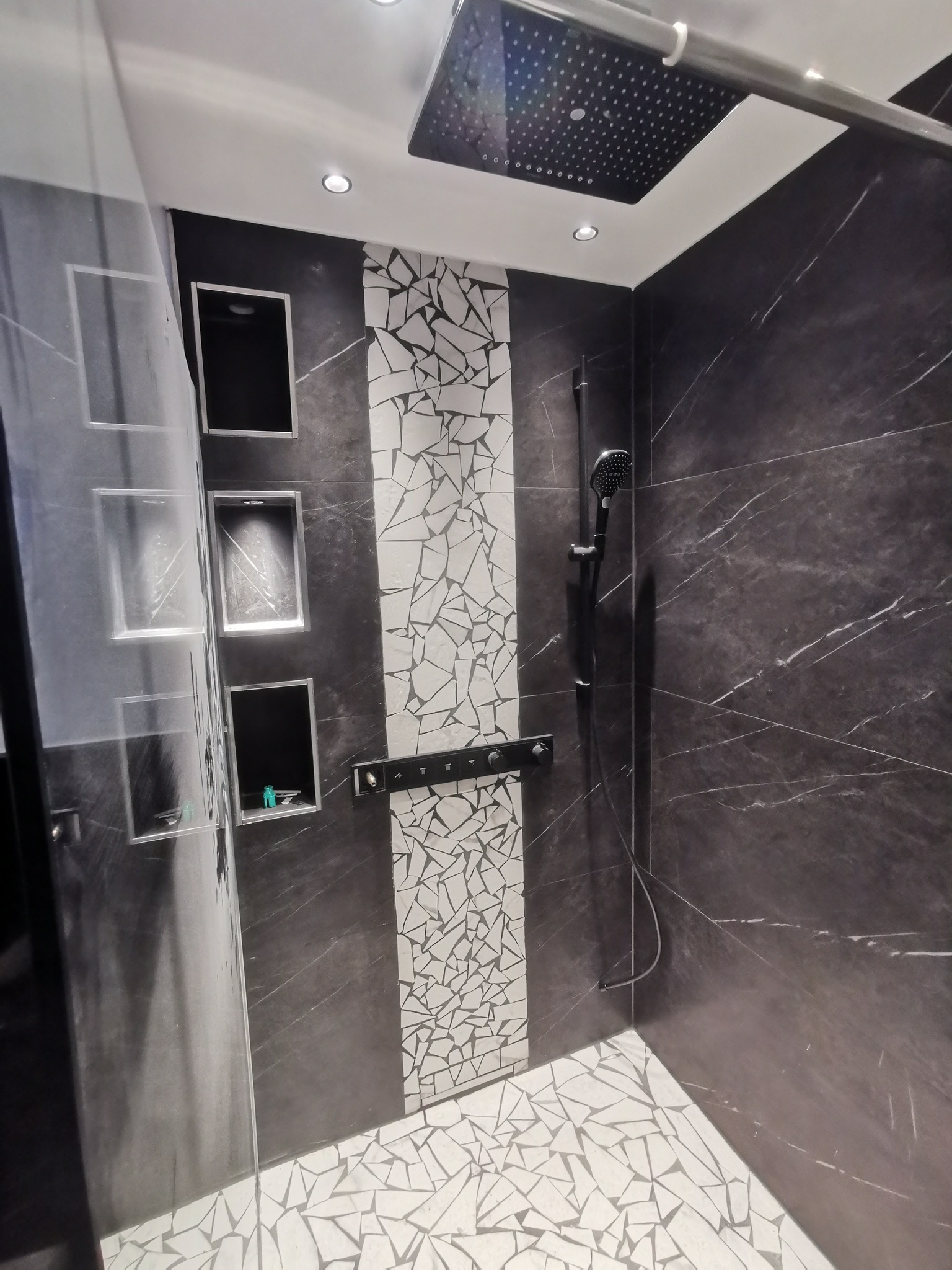 Detailansicht der begehbaren Mosaik-Dusche im Hauptbad mit beleuchteten Nischen