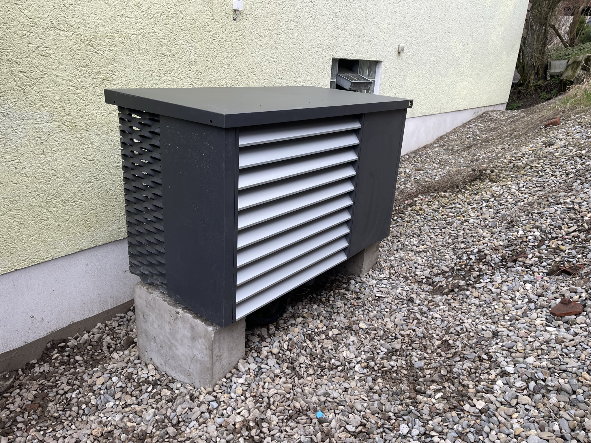 Außeneinheit der IDM-Wärmepumpe auf Betonfundament am Hang